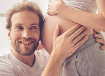 Dad listening to baby in mothers stomach