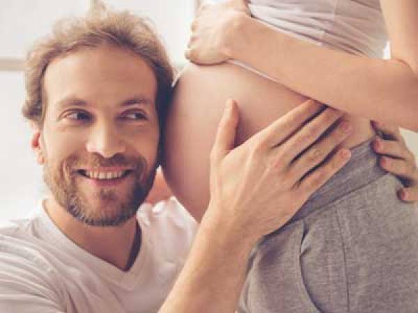 Dad listening to baby in mothers stomach