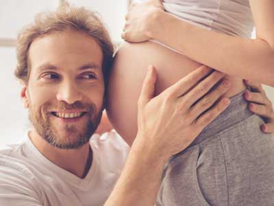 Dad listening to baby in mothers stomach