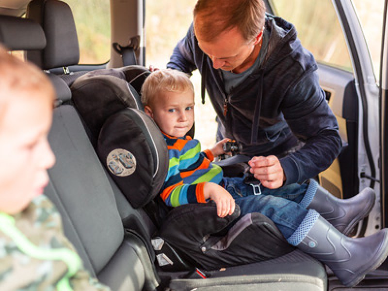 Dad putting child in car seat